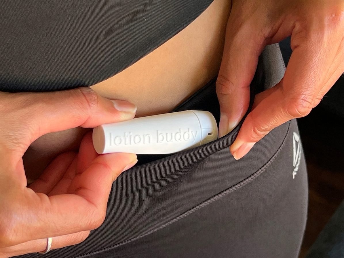 lotion buddy sliding into the small front pocket of a pair of leggings