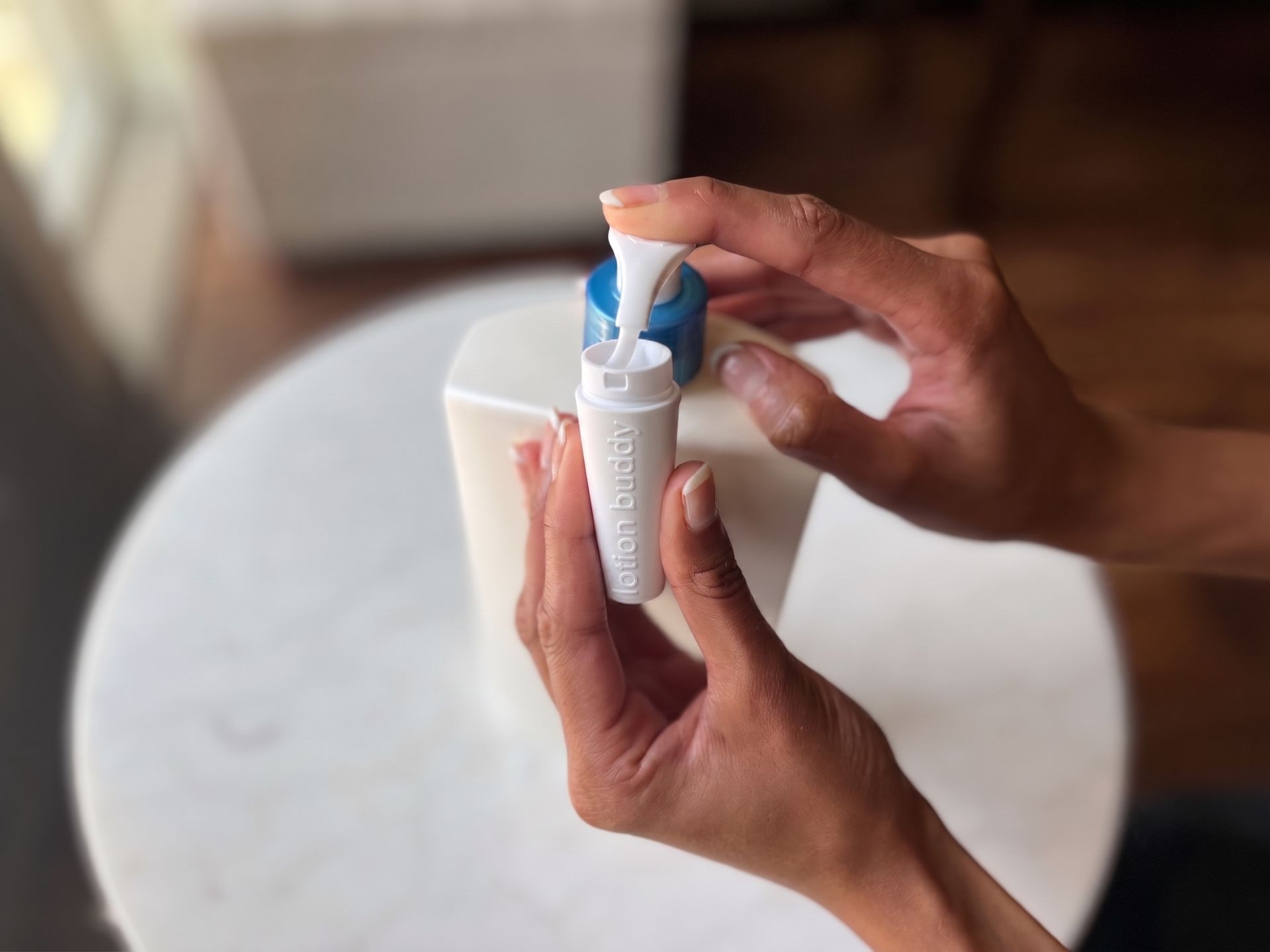 lotion buddy with its cap off, being refilled from a full-size lotion bottle